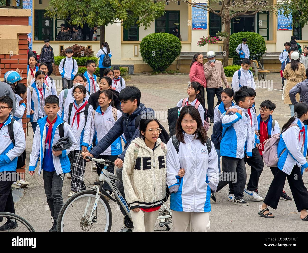 Schüler einer Mittelschule in Thanh Hoa, Vietnam, verlassen am 18. März 2025 ihre Schule nach dem Unterricht. Die Schüler tragen weiße und blaue Uniformen. Stockfoto