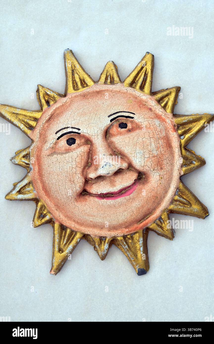 Gemaltes Gipsmodell einer lächelnden Sonnenpartie mit goldenen Strahlen Stockfoto