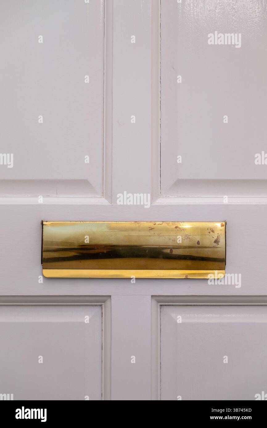 Goldenes Briefkästchen an einer weißen Tür. Alt und abgenutzt. Stockfoto