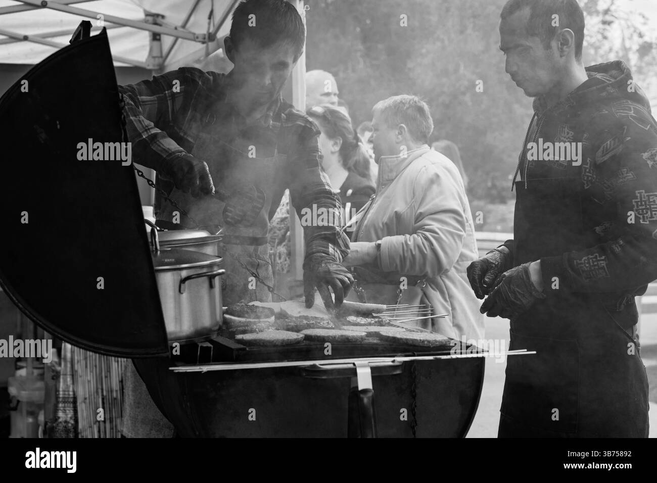 Zwei Personen kochen zusammen köstliche Speisen, während Dampf vom heißen Grill steigt. Harrogate, Yorkshire, Großbritannien. Stockfoto