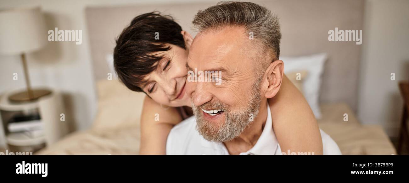 Ein Paar mittleren Alters umarmt sich glücklich zu Hause, zeigt Liebe und Gemeinschaft zusammen, Banner Stockfoto