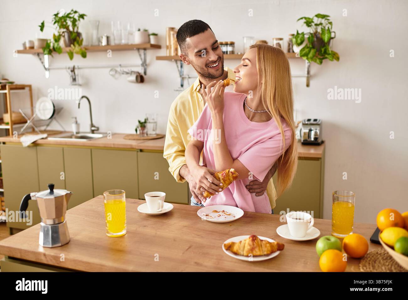 Ein Paar nimmt es glücklich ein, während es ein wunderbares Frühstück in seiner einladenden Küche genießt. Stockfoto