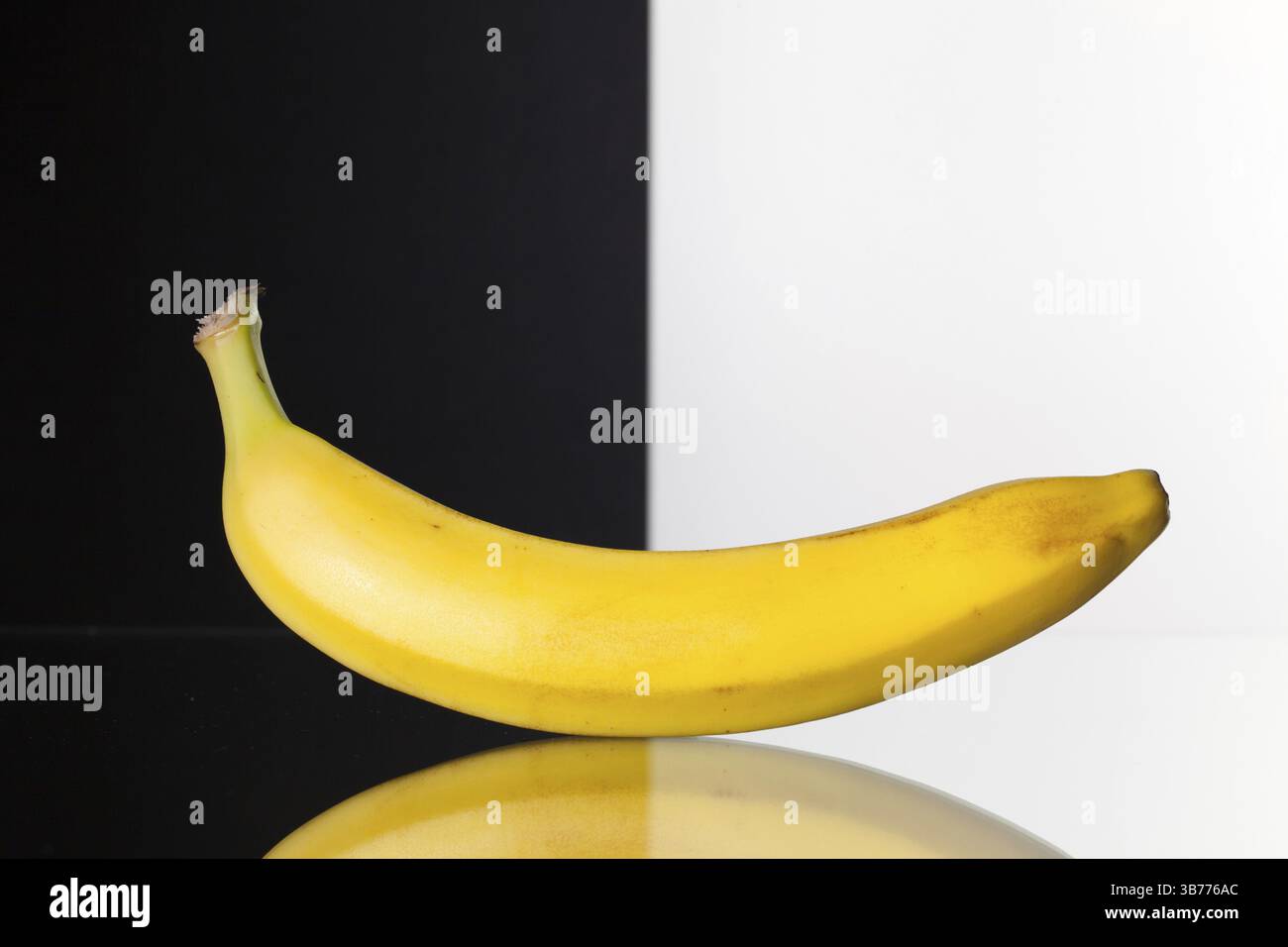 Einzige Banane isoliert auf schwarzen und weißen Hintergrund und Glas Schreibtisch Stockfoto