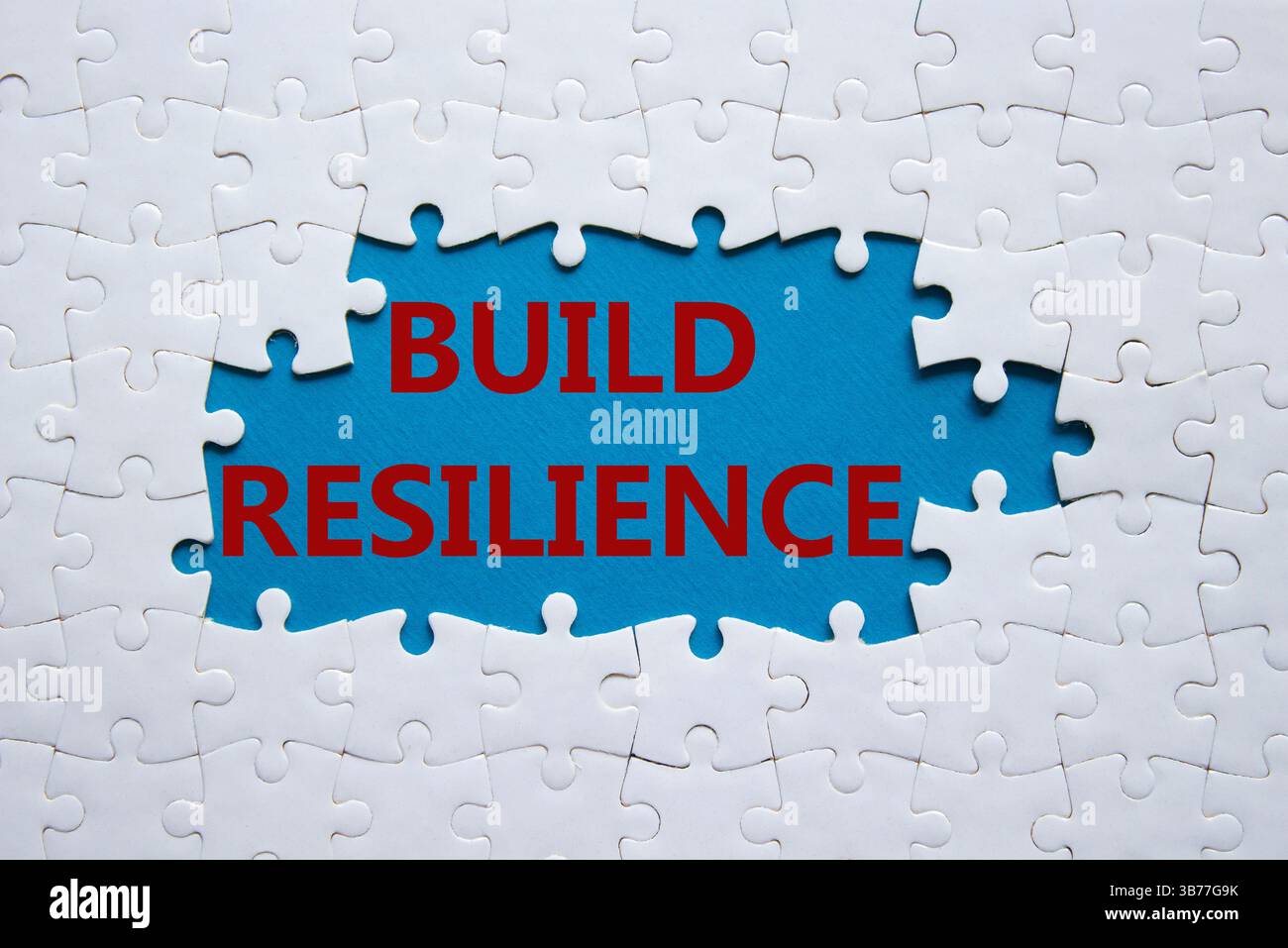 Symbol für Belastbarkeit erstellen. Weißes Puzzle mit Wörtern schafft Widerstandsfähigkeit. Wunderschöner blauer Hintergrund. Business- und Build Resilience-Konzept. Kopierbereich. Stockfoto