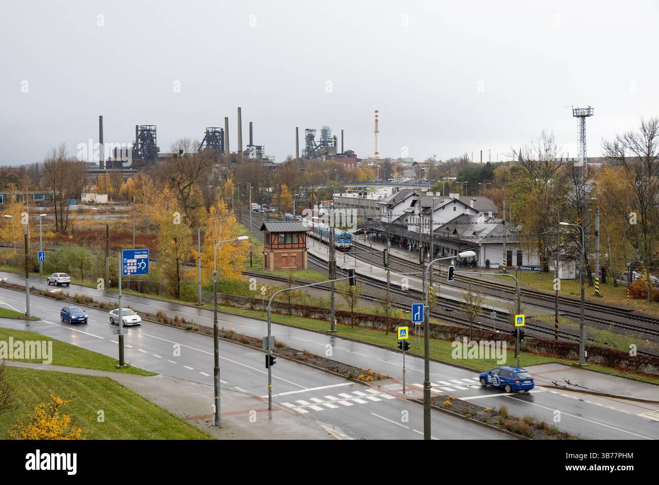 OSTRAVA, TSCHECHISCHE REPUBLIK - 24. NOVEMBER 2023: Zug im Bahnhof Ostrava-Stred vor dem Wiederaufbau, Kohlebergwerke und Schornsteine im Hintergrund Stockfoto