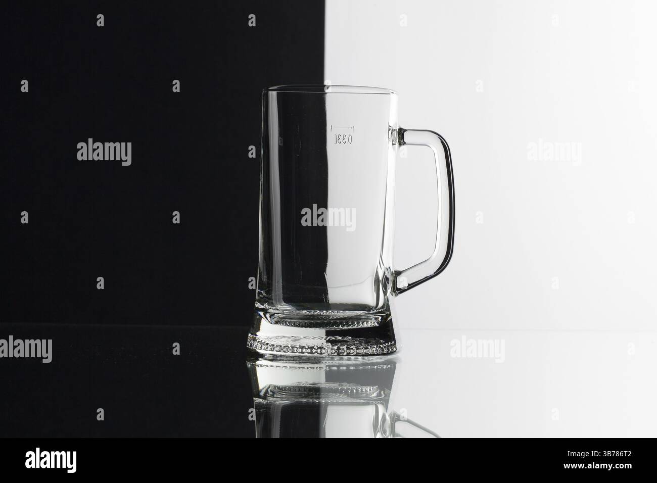 Glas Bier auf dem schwarzen und weißen Hintergrund auf dem Glastisch Stockfoto