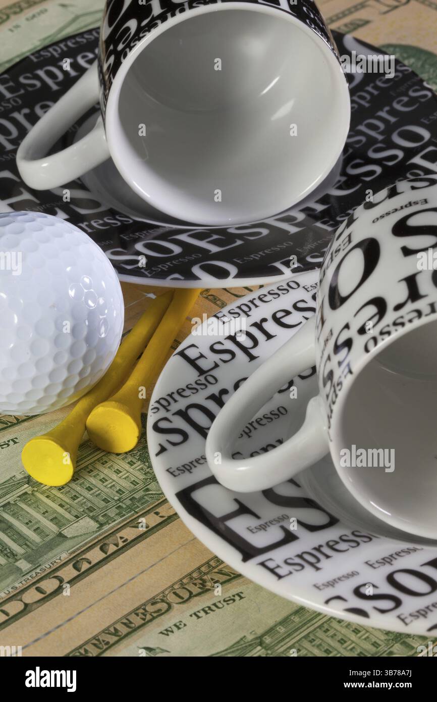 Zwei leere Kaffeetassen und Golf-Ausrüstungen liegen auf US-Dollar-Banknoten Stockfoto