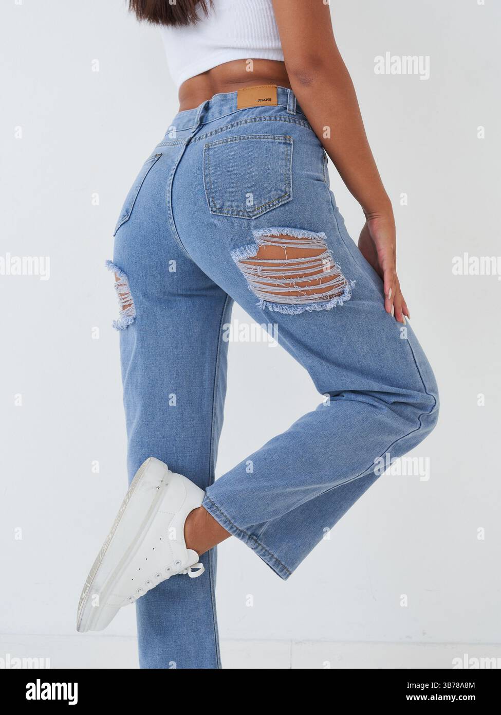 Frau mit zerrissenen Jeans und Sneakers Stockfoto