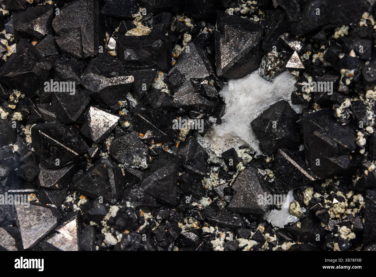 Magnetit ist ein Mineral und eines der wichtigsten Eisenerze. Nahaufnahme von schwarzen metallischen Kristallformationen, die in geometrischen Mustern gegen einen Text angeordnet sind Stockfoto