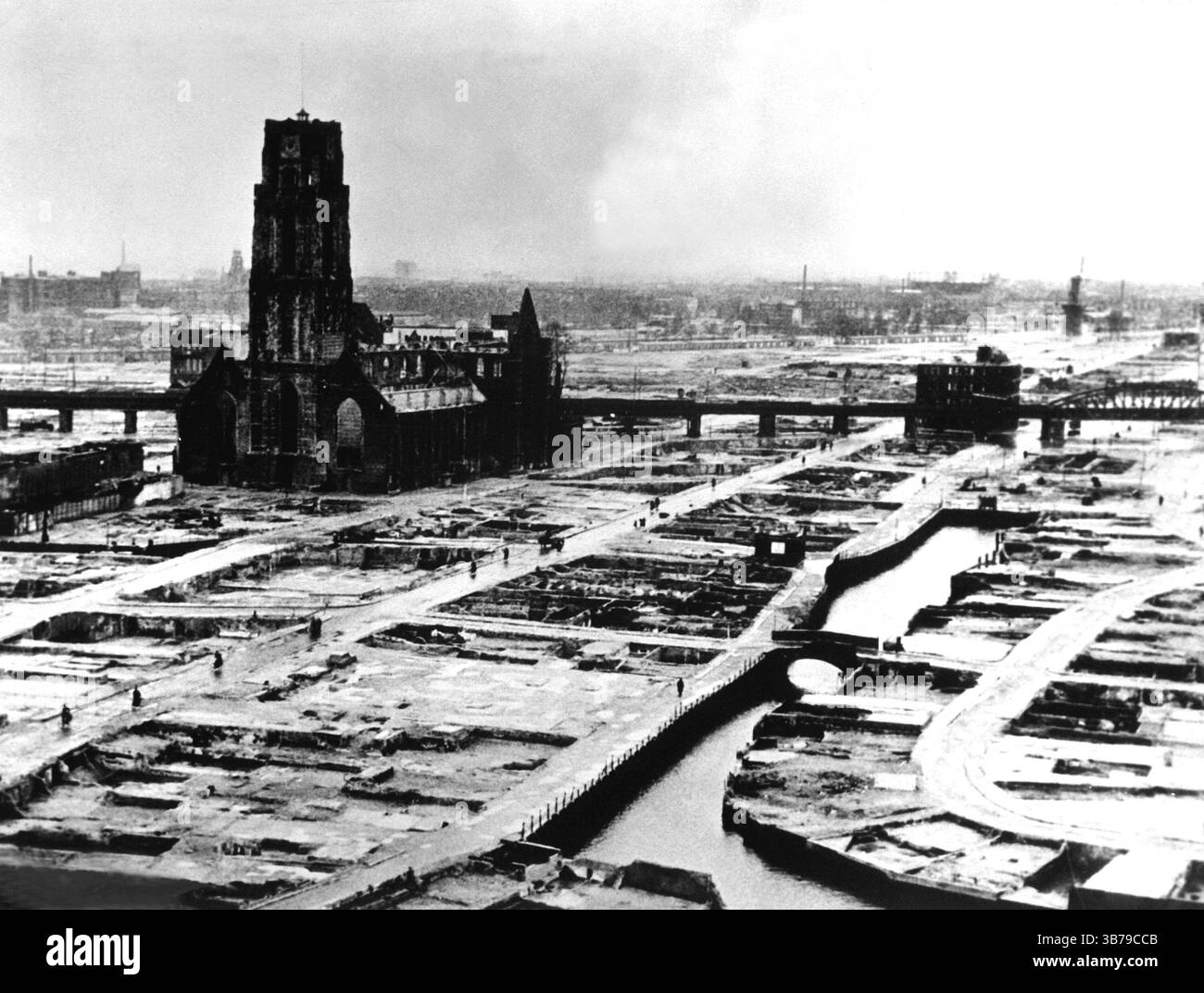 1940 wurde Rotterdam während der deutschen Invasion in die Niederlande während des Zweiten Weltkriegs von der Luftwaffe schweren Luftangriffen ausgesetzt. Ziel war es, die in der Stadt kämpfenden deutschen Truppen zu unterstützen, den niederländischen Widerstand zu brechen und die niederländische Armee zur Kapitulation zu zwingen. Die Bombenangriffe begannen mit Beginn der Feindseligkeiten am 10. Mai und gipfelten mit der Zerstörung des gesamten historischen Stadtzentrums am 14. Mai. Auf diesem Foto, das nach der Reinigung der Trümmer aufgenommen wurde, ist die St. Laurence Church beschädigt, steht aber noch. Stockfoto