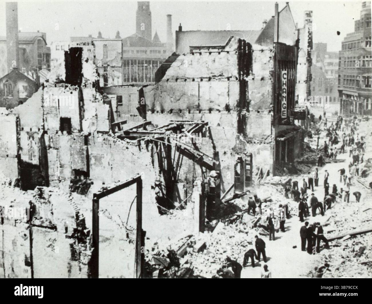 1940 wurde Rotterdam während der deutschen Invasion in die Niederlande während des Zweiten Weltkriegs von der Luftwaffe schweren Luftangriffen ausgesetzt. Ziel war es, die in der Stadt kämpfenden deutschen Truppen zu unterstützen, den niederländischen Widerstand zu brechen und die niederländische Armee zur Kapitulation zu zwingen. Die Bombenangriffe begannen mit Beginn der Feindseligkeiten am 10. Mai und gipfelten mit der Zerstörung des gesamten historischen Stadtzentrums am 14. Mai. Dieses Bild zeigt Zivilisten, die nach dem Angriff die Straßen räumen. Stockfoto