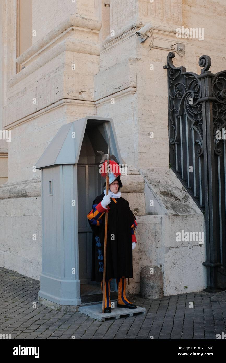 Die Schweizergarde in traditionellen Renaissanceuniformen stehen am Posten in der Nähe des Eingangs zur Vatikanstadt mit historischen Steinbögen und Wachkabinen. Hochwertige Fotos Stockfoto
