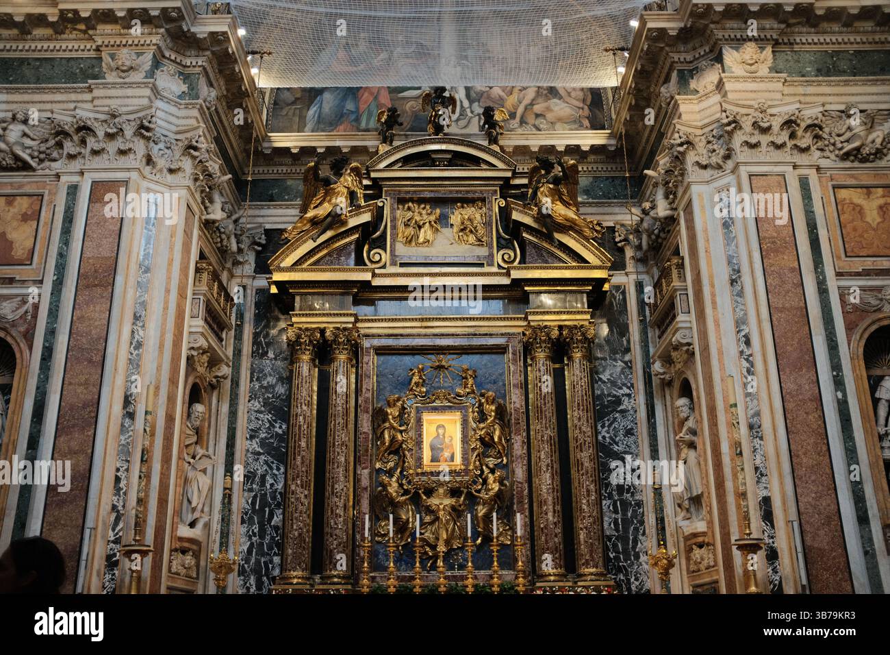 Goldenes Symbol des Salus Populi Romani, flankiert von kunstvollen korinthischen Säulen, vergoldeten Skulpturen und dekorativen Marmorwänden in der Basilika Santa Maria Major Rom Italien. Hochwertige Fotos Stockfoto