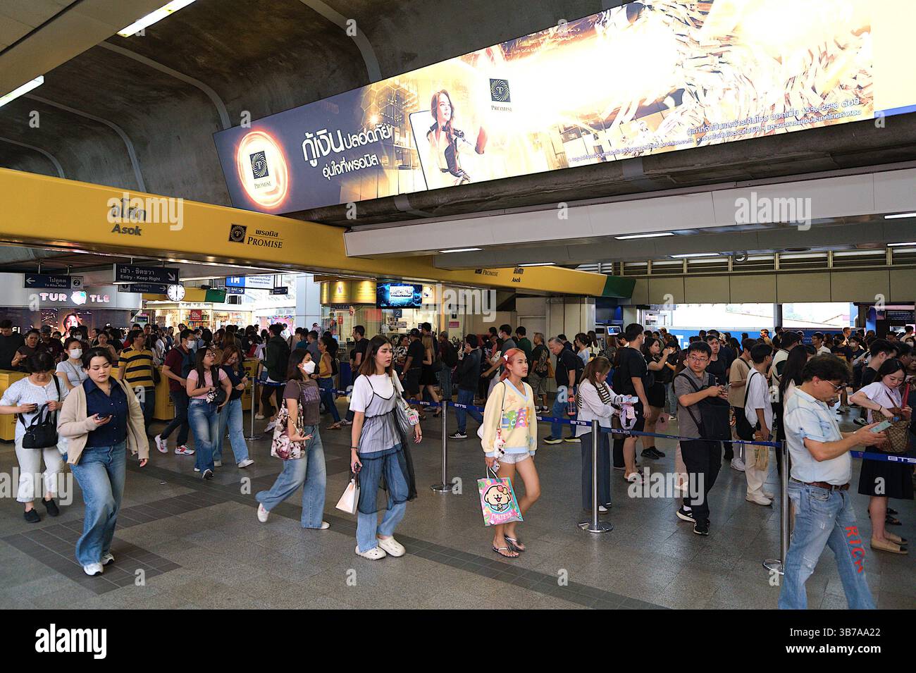Abendliche Menschenmassen an den Gantry zur Asok BTS Skytrain Station, einem geschäftigen Autobahnkreuz, der mit der U-Bahn-Linie MRT Blue Line in Sukhumvit, Bangkok, verbunden ist Stockfoto