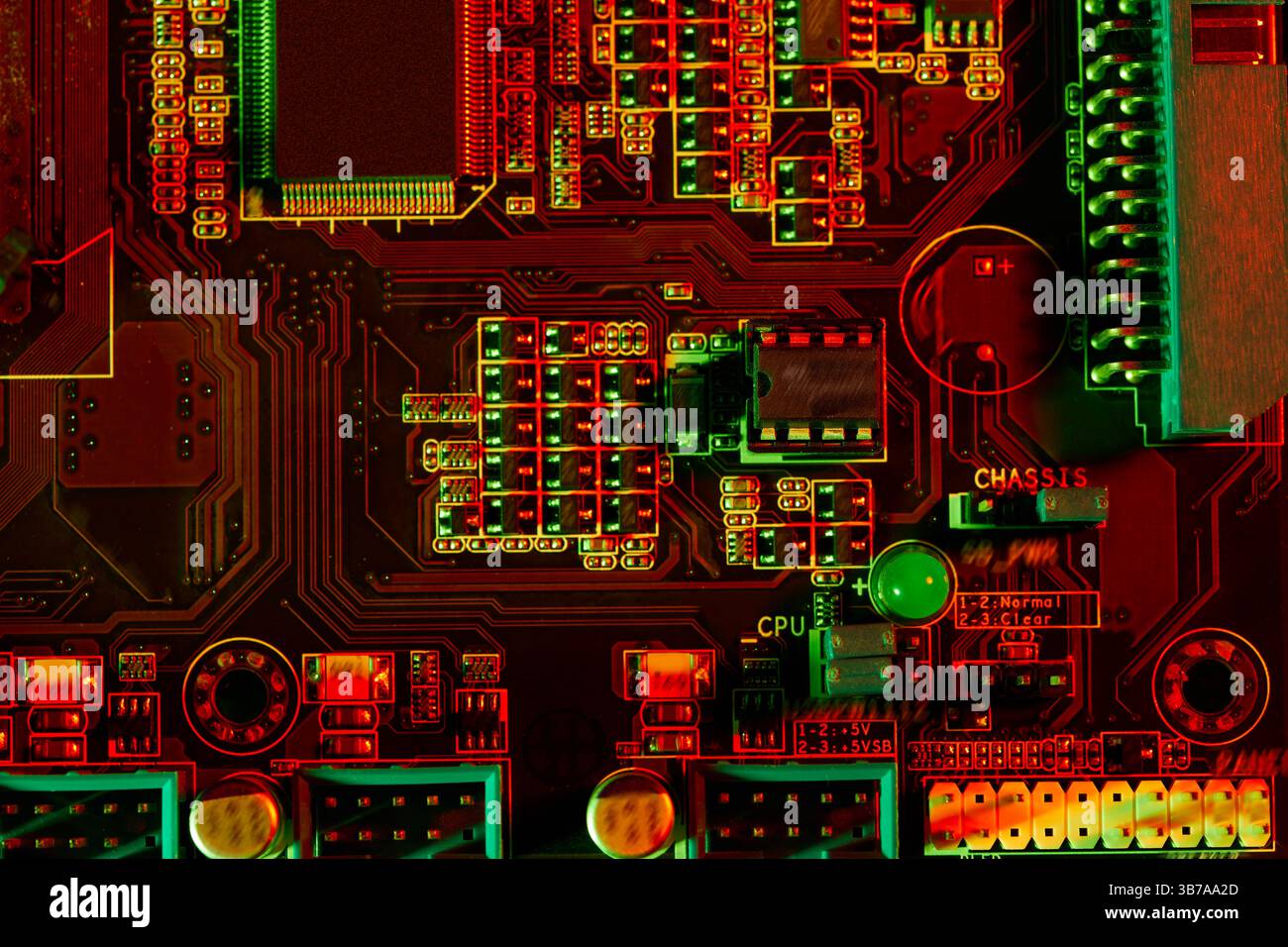 Nahaufnahme eines Motherboards mit integrierten Schaltungen und Anschlüssen unter roter und grüner Beleuchtung, wodurch ein High-Tech, komplexer und futuristischer Eindruck entsteht Stockfoto