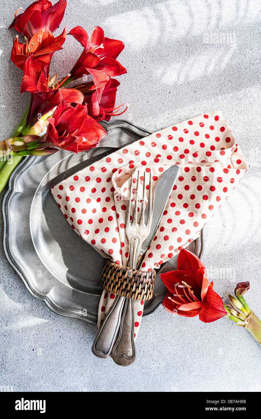 Silbernes Besteck und Teller, amaryllis-Dekoration und Serviette mit gepunkteten Stoffen Stockfoto