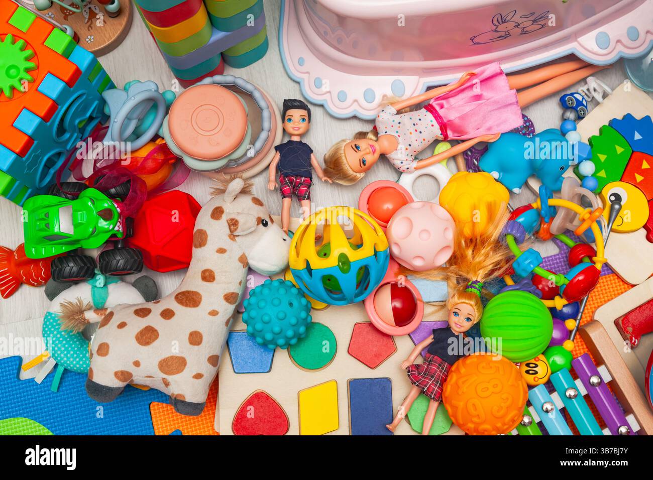 Ein Haufen verschiedener Kinderspielzeuge, verstreut auf einer Spielmatte. Stockfoto