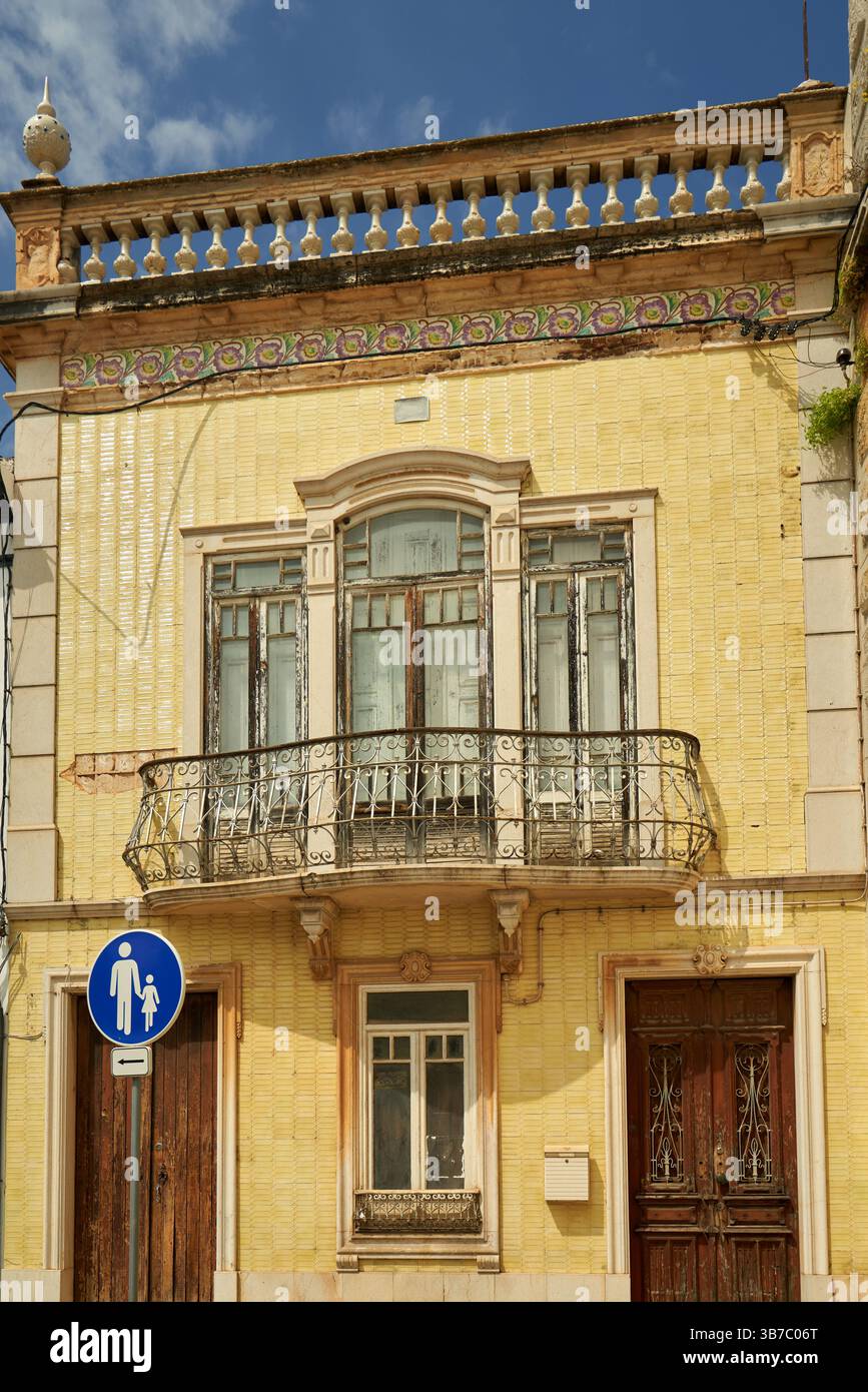 Haus mit gemusterten gelben Fliesen und verziertem Balkon in Tavira, Portugal. Stockfoto