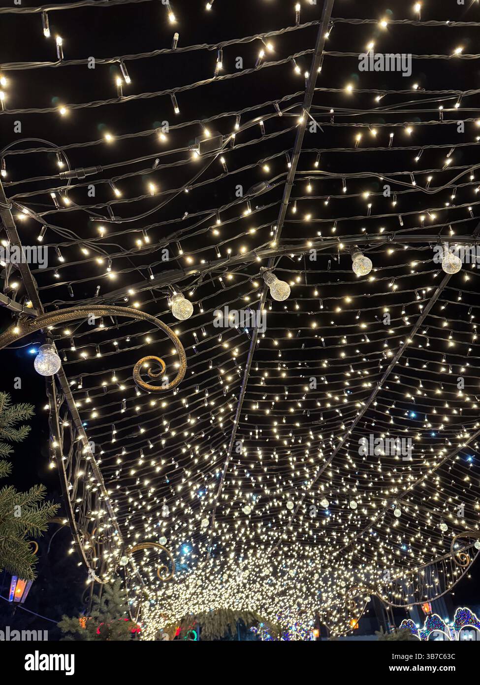 Bezaubernder Nachthimmel mit leuchtenden Lichtern, die eine magische Atmosphäre in einer festlichen Outdoor-Umgebung unter den Sternen schaffen. Stockfoto