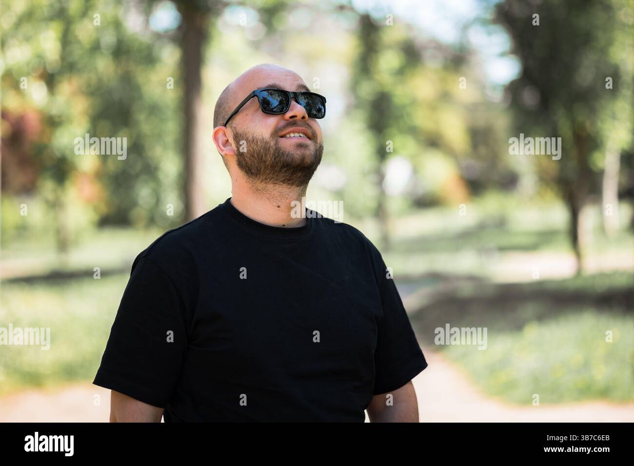 Porträt eines Mannes mit Bart und Sonnenbrille, der nach oben blickt. Stockfoto