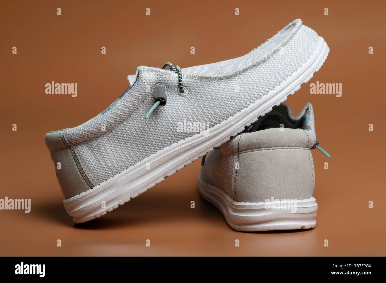 Paar graue, helle Schuhe isoliert auf braunem Hintergrund Stockfoto