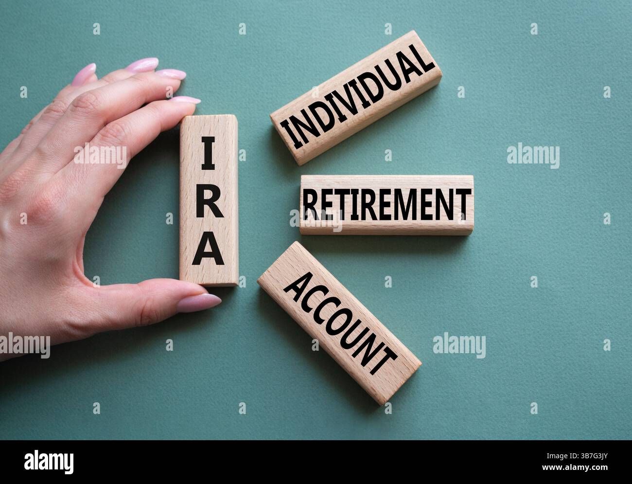 IRA - Symbol für individuelles Abgangskonto. Konzeptwort IRA auf Holzblöcken. Geschäftsmann Hand. Wunderschöner graugrüner Hintergrund. Geschäftliche und IRA-Kontrakte Stockfoto