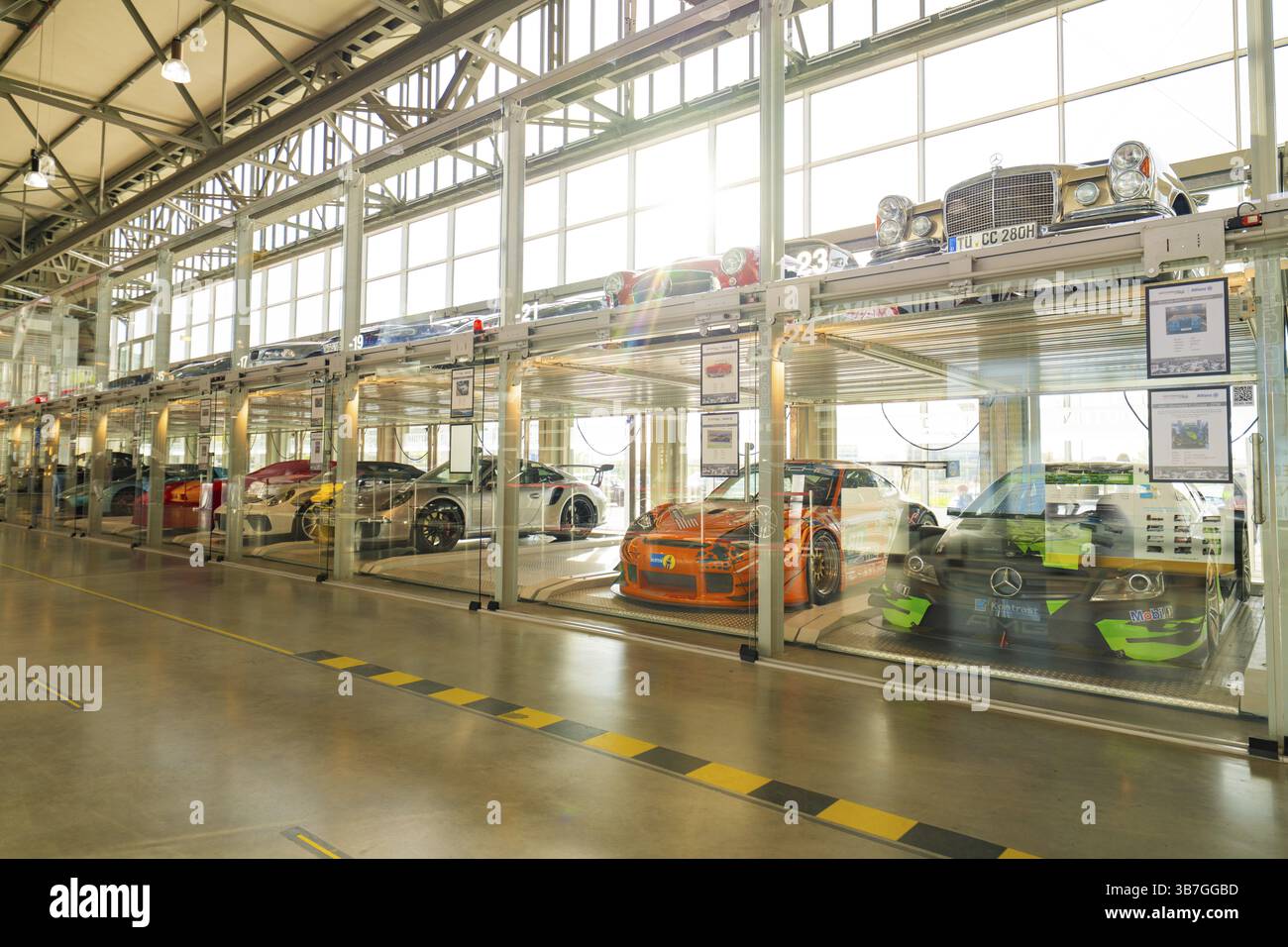 Autos in einer zweigeschossigen Glasgarage mit natürlichem Tageslicht und minimalistischem Design, Motorworld Boeblingen, Deutschland, Europa Stockfoto