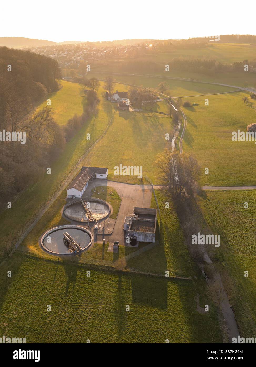 Kläranlage umgeben von grünen Feldern und Bäumen, bei Sonnenuntergang in einer ruhigen ländlichen Gegend, Gechingen, Bezirk Calw, Schwarzwald, Deutschland Stockfoto