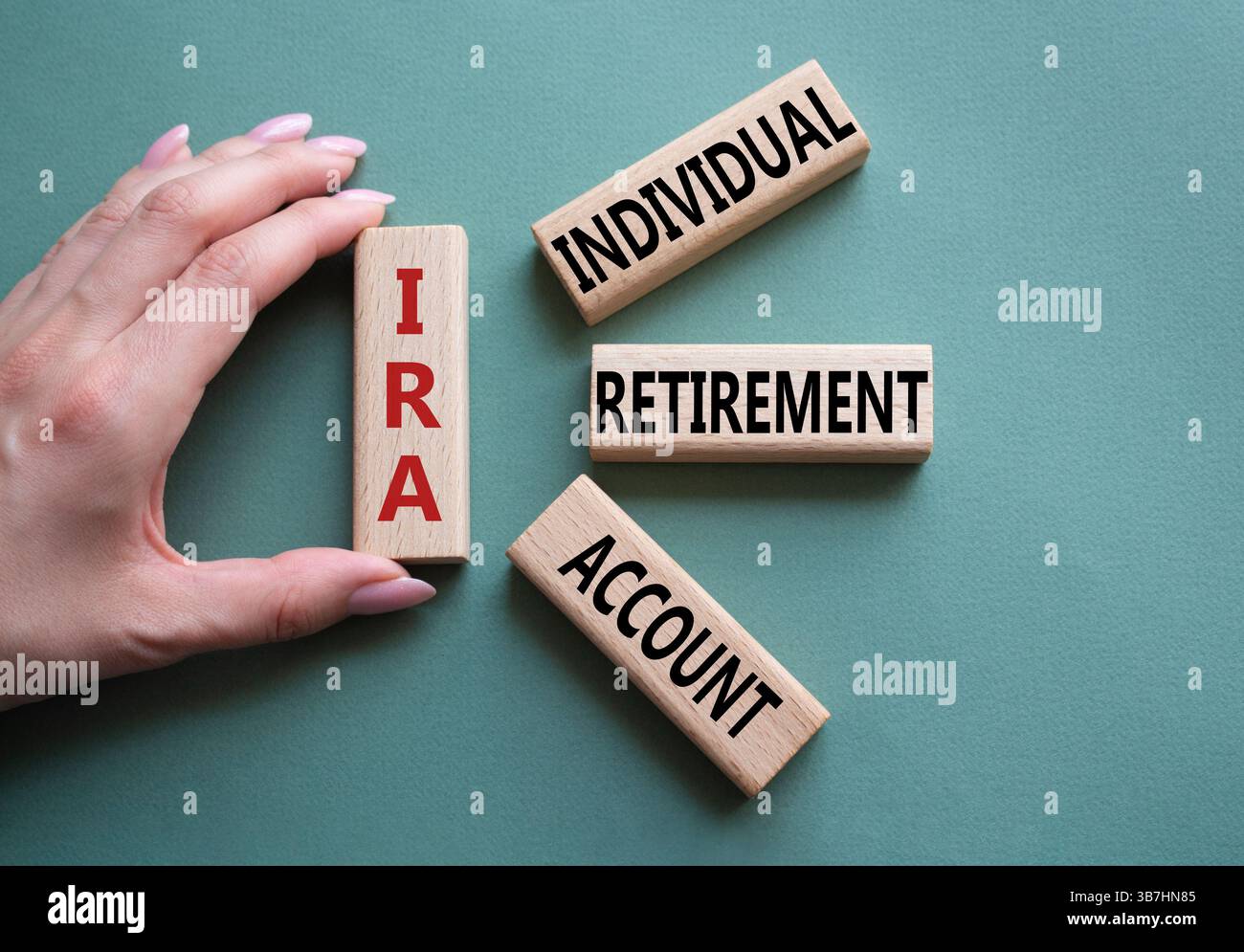 IRA - Symbol für individuelles Abgangskonto. Konzeptwort IRA auf Holzblöcken. Geschäftsmann Hand. Wunderschöner graugrüner Hintergrund. Geschäftliche und IRA-Kontrakte Stockfoto