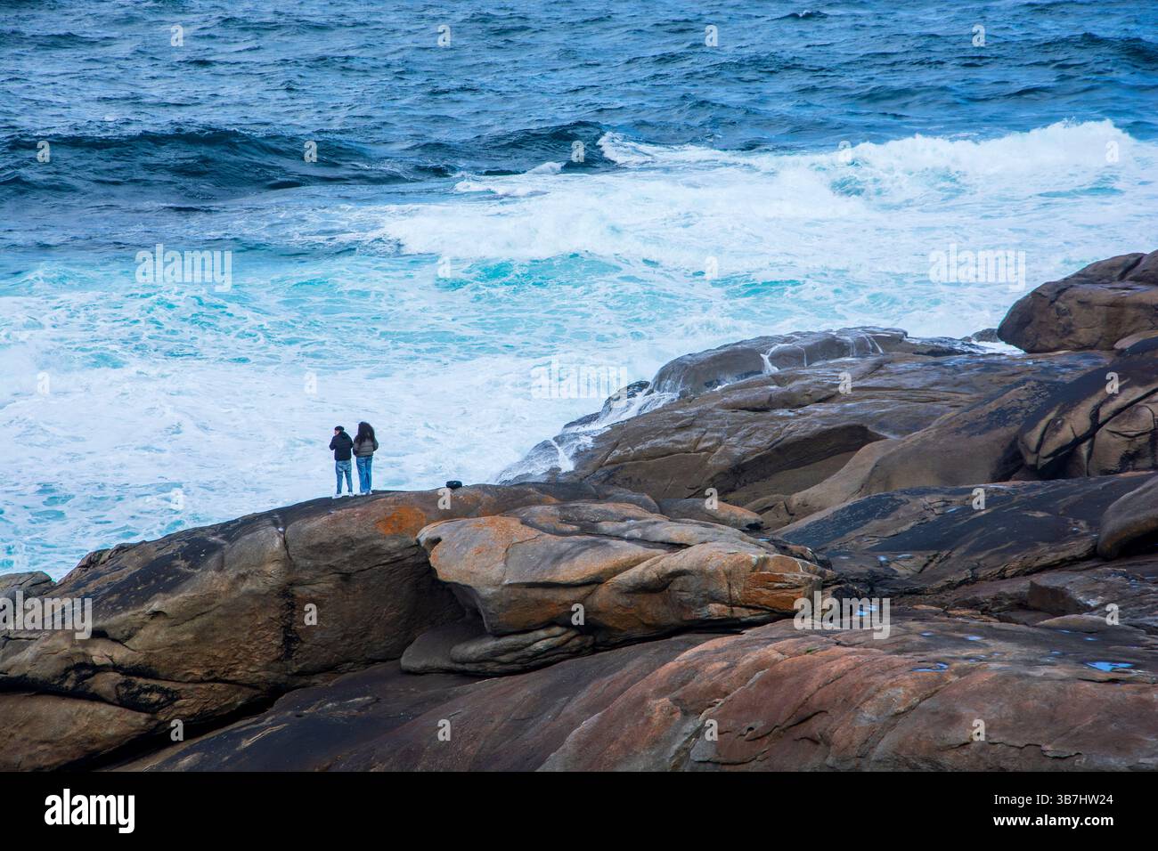 Ein Paar auf der Klippe mit Blick auf den Atlantik an der Küste von Galícia, in Muxia, Spanien. Stockfoto Ein Paar auf der Klippe mit Blick auf den Atlantik an der Küste von Galícia, in Muxia, Spanien. Stockfoto