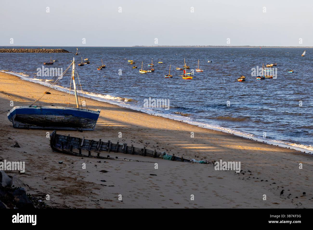 Kleines Fischerboot am Strand, neben einem teilweise vergrabenen Schiffswrack Stockfoto