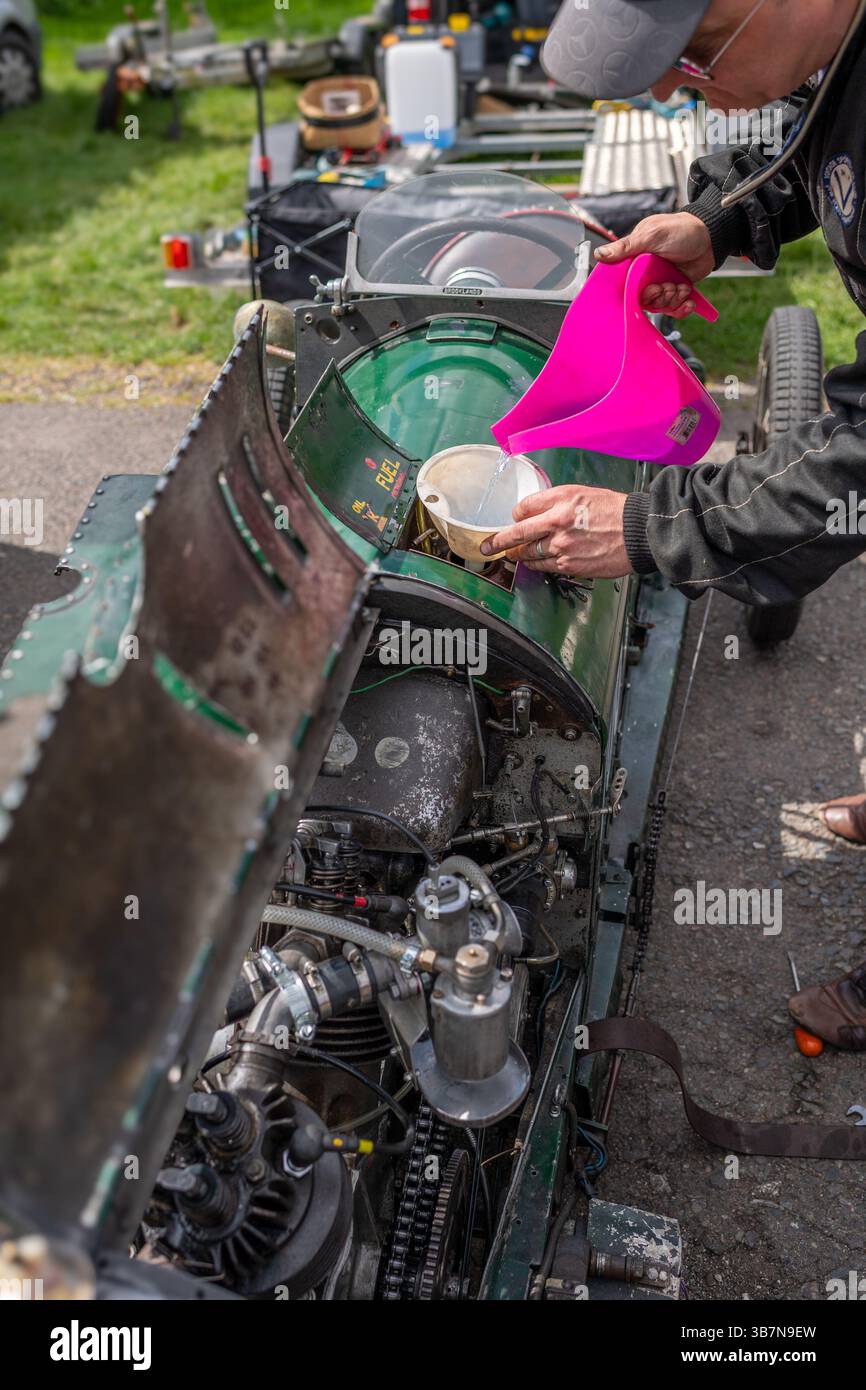 Mechaniker, der bei einem VSCC-Rennen den Kraftstofftank bei einem klassischen Jag Areo Special Einsitzer über einem Top-Sportwagen auffüllt. Stockfoto