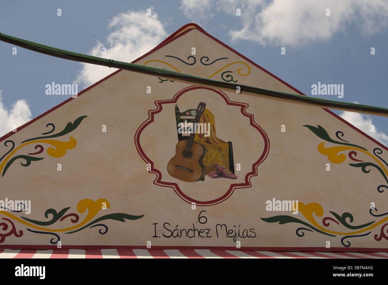 Handgemalte Caseta-Fassade in La Feria de Sevilla 2025 mit spanischer Gitarre und Schal, die Flamenco und andalusische Kultur symbolisieren. Stockfoto