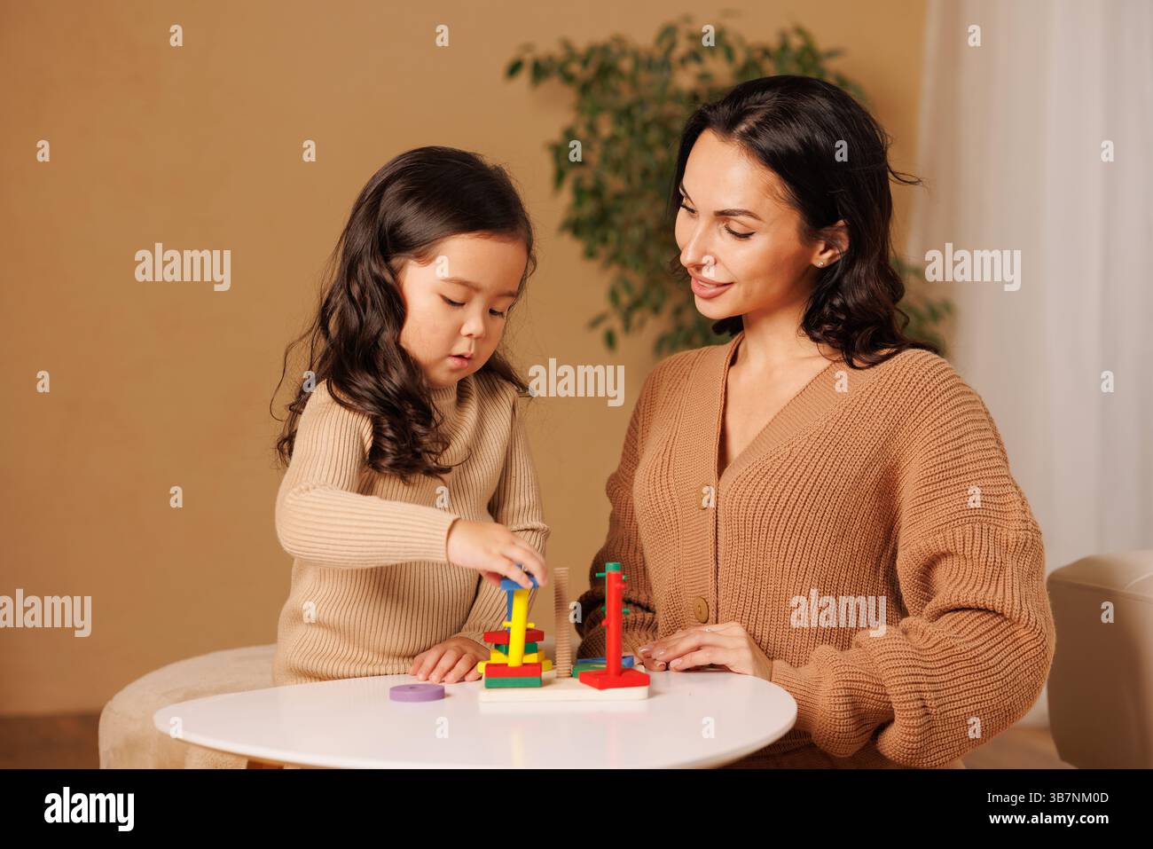Mutter und Tochter spielen zusammen mit pädagogischem Holzspielzeug und fördern so das Lernen, die Entwicklung und die Bindung. Stockfoto