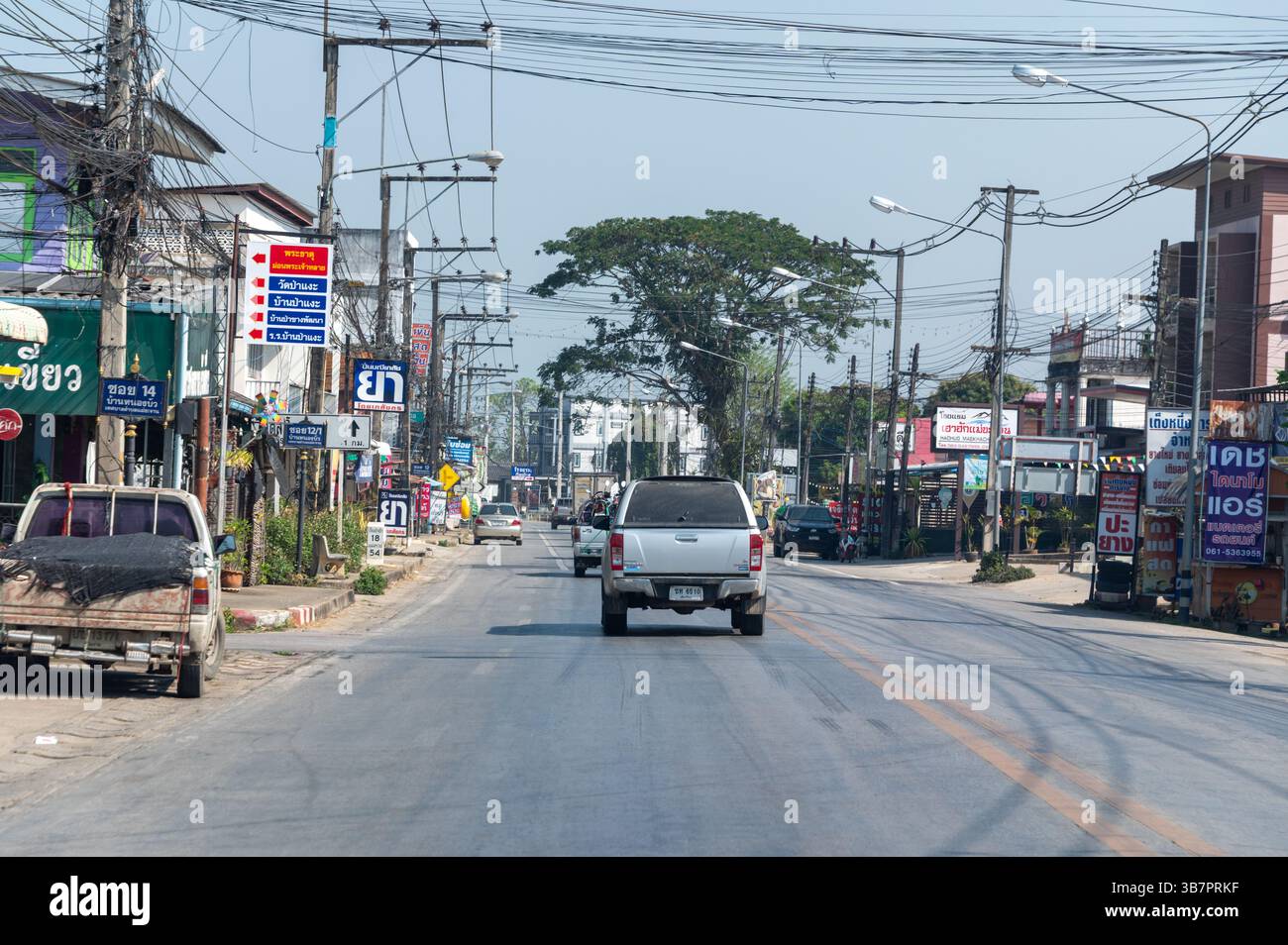 Vorbei an einer kleinen Stadt mit schweren Kabeln auf der Hauptstraße Chiang Mai/Chiang Rai im Norden Thailands Stockfoto