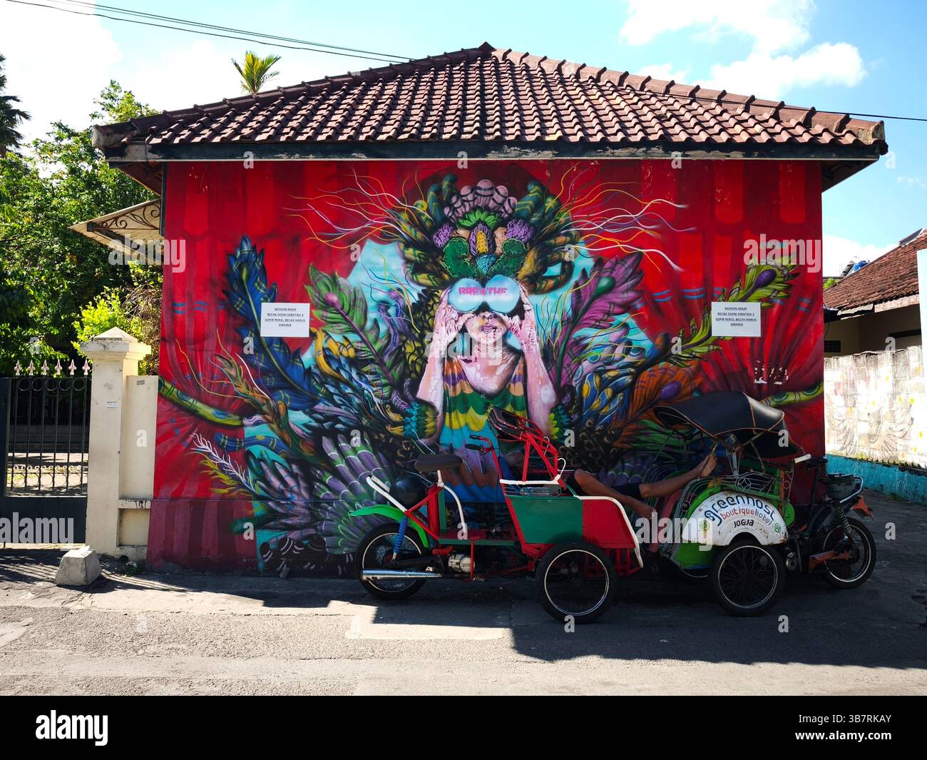 Ein Gebäude mit einem coolen Wandgemälde, das auch ein Ort für Pedicab-Fahrer ist, um eine Pause einzulegen Stockfoto