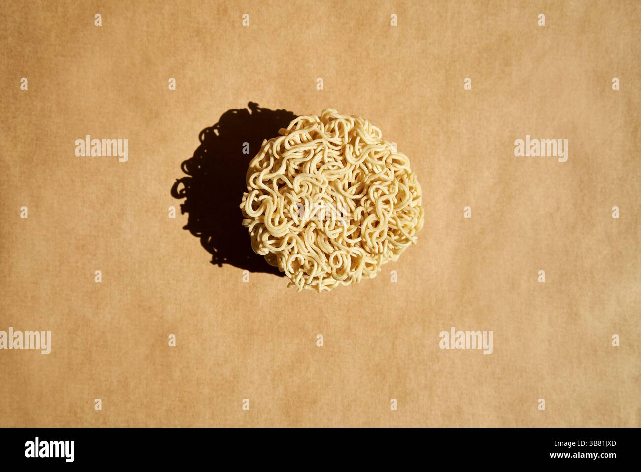 Runder Block trockener Instant-Nudeln auf braunem Hintergrund. Lebensmittelkonzept Stockfoto