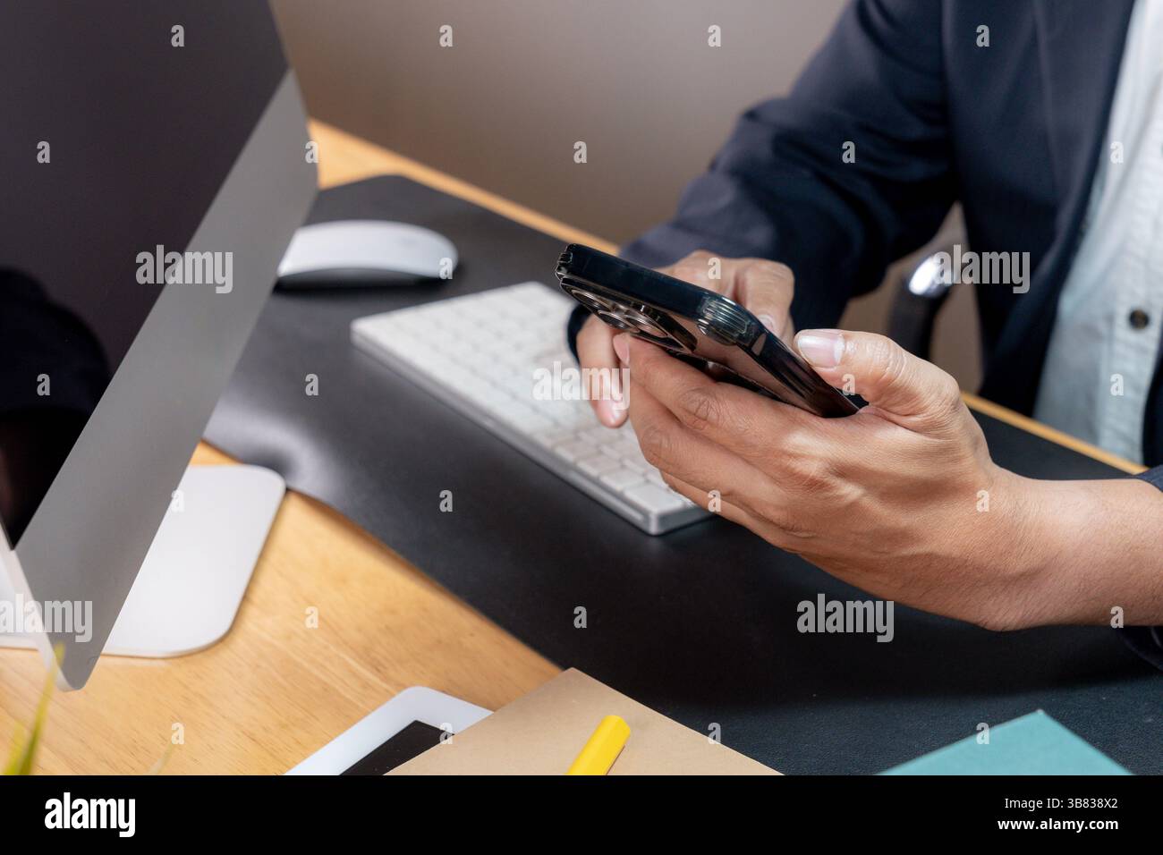 Teilansicht eines fokussierten Geschäftsmannes beim Multitasking, der ein Telefon am Ohr hält, während er auf einer Computertastatur schreibt Stockfoto