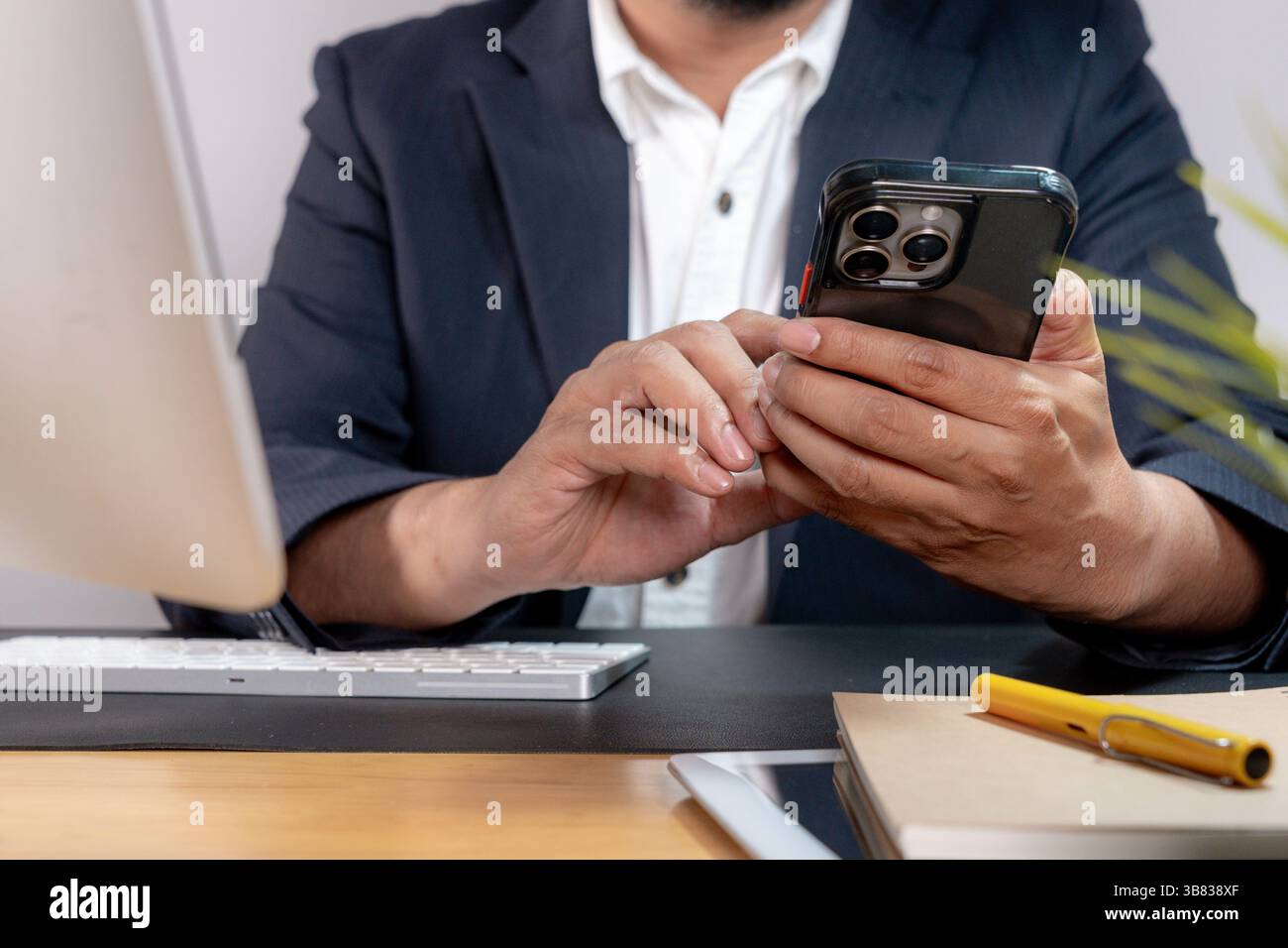 Teilansicht eines fokussierten Geschäftsmannes beim Multitasking, der ein Telefon am Ohr hält, während er auf einer Computertastatur schreibt Stockfoto