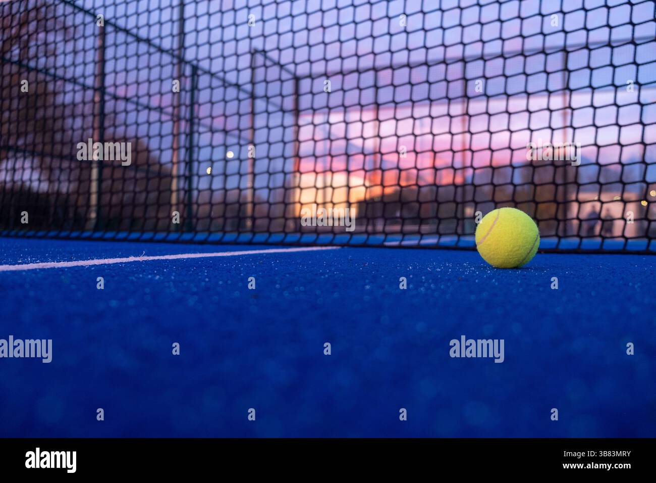 Oberflächennahe Ansicht des Paddelballs auf einem blauen Padel-Tennisplatz bei Sonnenuntergang, Hintergrund des Racket-Sportkonzepts Stockfoto