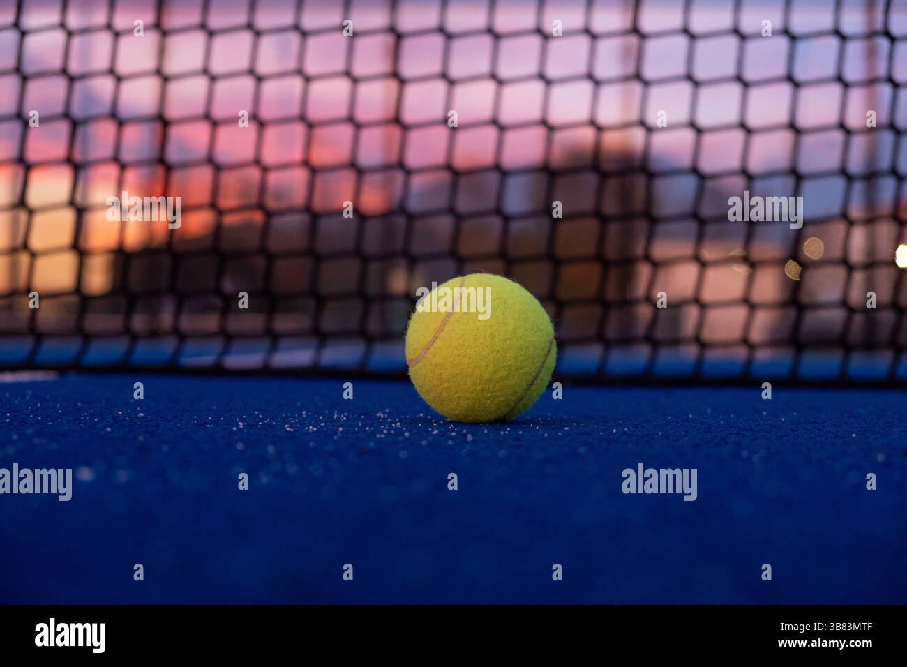 Oberflächennahe Ansicht des Padel-Balls auf einem blauen Paddle-Tennisplatz bei Sonnenuntergang, Hintergrund des Racket-Sportkonzepts Stockfoto