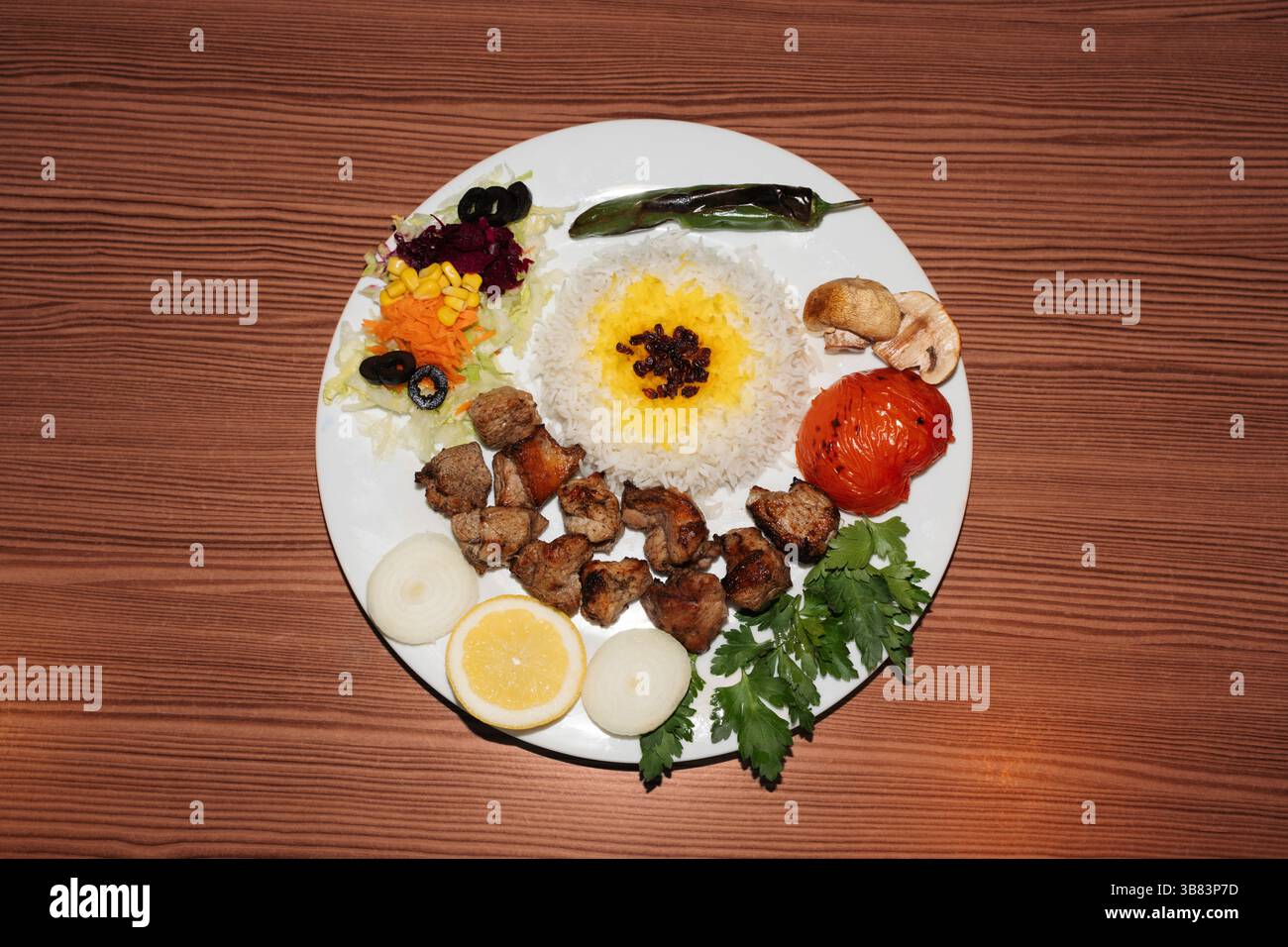 Türkischer Kebab-Teller mit Reis und Salat auf hölzernem Hintergrund. Retro-Flash-Lebensmittelfotografie Stockfoto