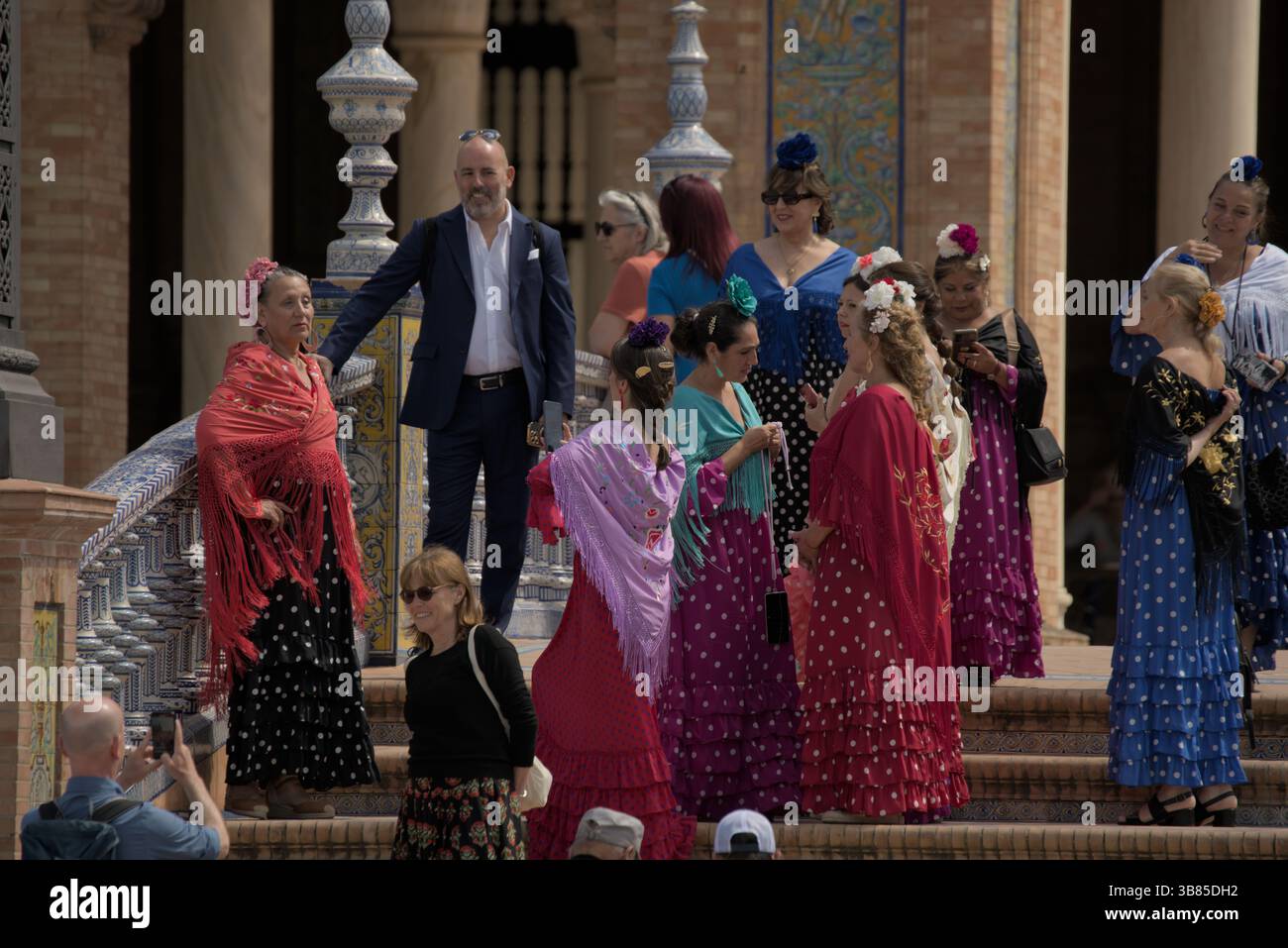 Gruppe von Frauen in bunten Flamenco-Kleidern auf der Plaza de España während der Feria de Sevilla 2025, Sevilla, Andalucía, Spanien. Stockfoto