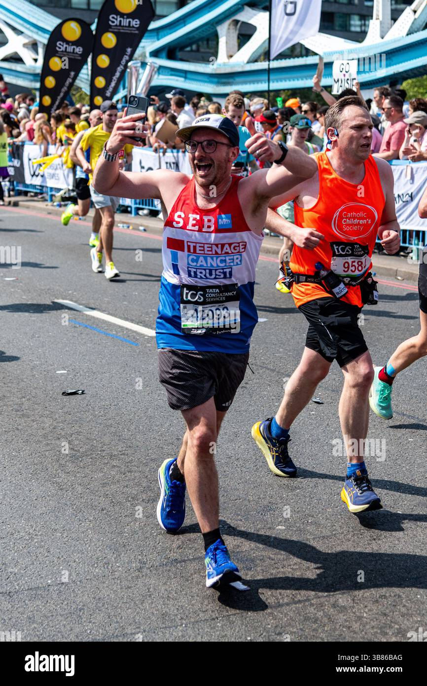 Läufer, die beim London Marathon 2025 für die Stiftung Teenage Cancer Trust auf der Tower Bridge in Central London, Großbritannien, laufen Stockfoto