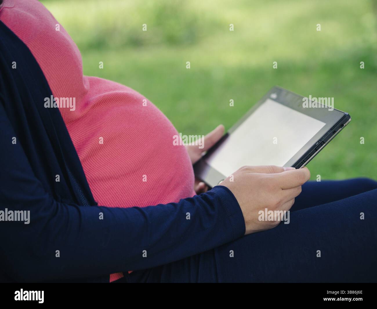 Schwangere Frau mit Tablet-E-Reader Stockfoto