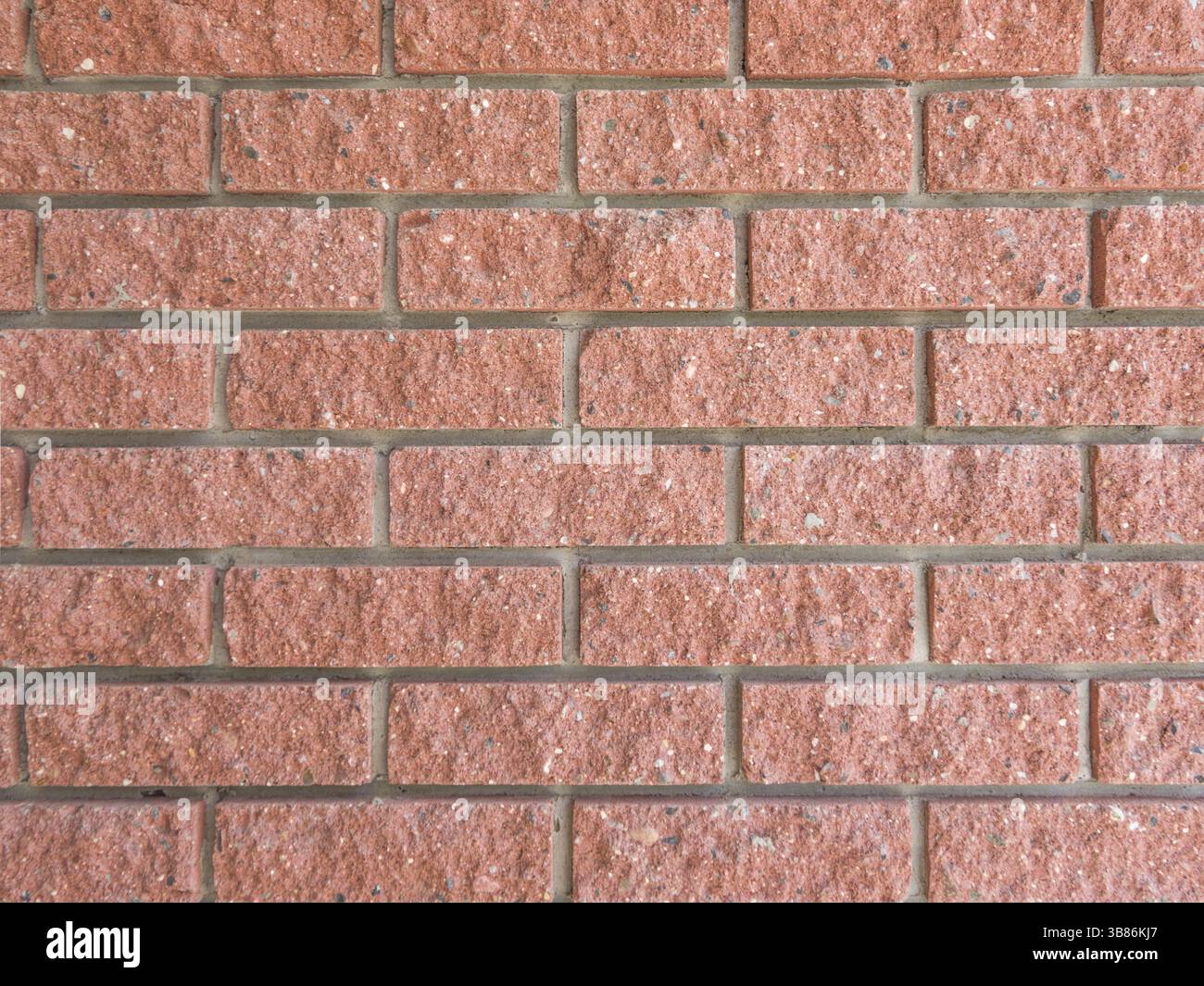 Eine Mauer aus einer künstlichen grauen Steinfassade mit rauen, gebrochenen Oberflächen, die als Ziegelstein angelegt wurden Stockfoto