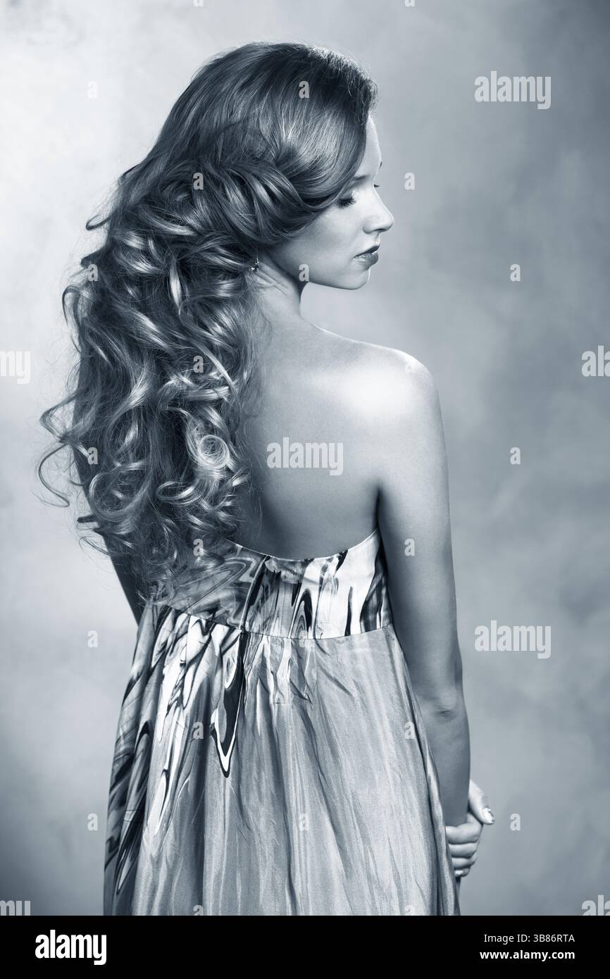 Schönes Modell mit langem lockigem Haar und professionellem Make-up. Modisches Make-up und Haarlocken Stockfoto
