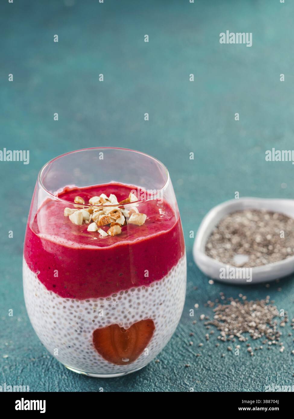 Idee für gesundes Frühstück am Valentinstag: Chia Pudding mit roten Beeren Püree, gehackte Mandeln auf und Erdbeere in der Form des Herzens. Kopieren Sie sp Stockfoto
