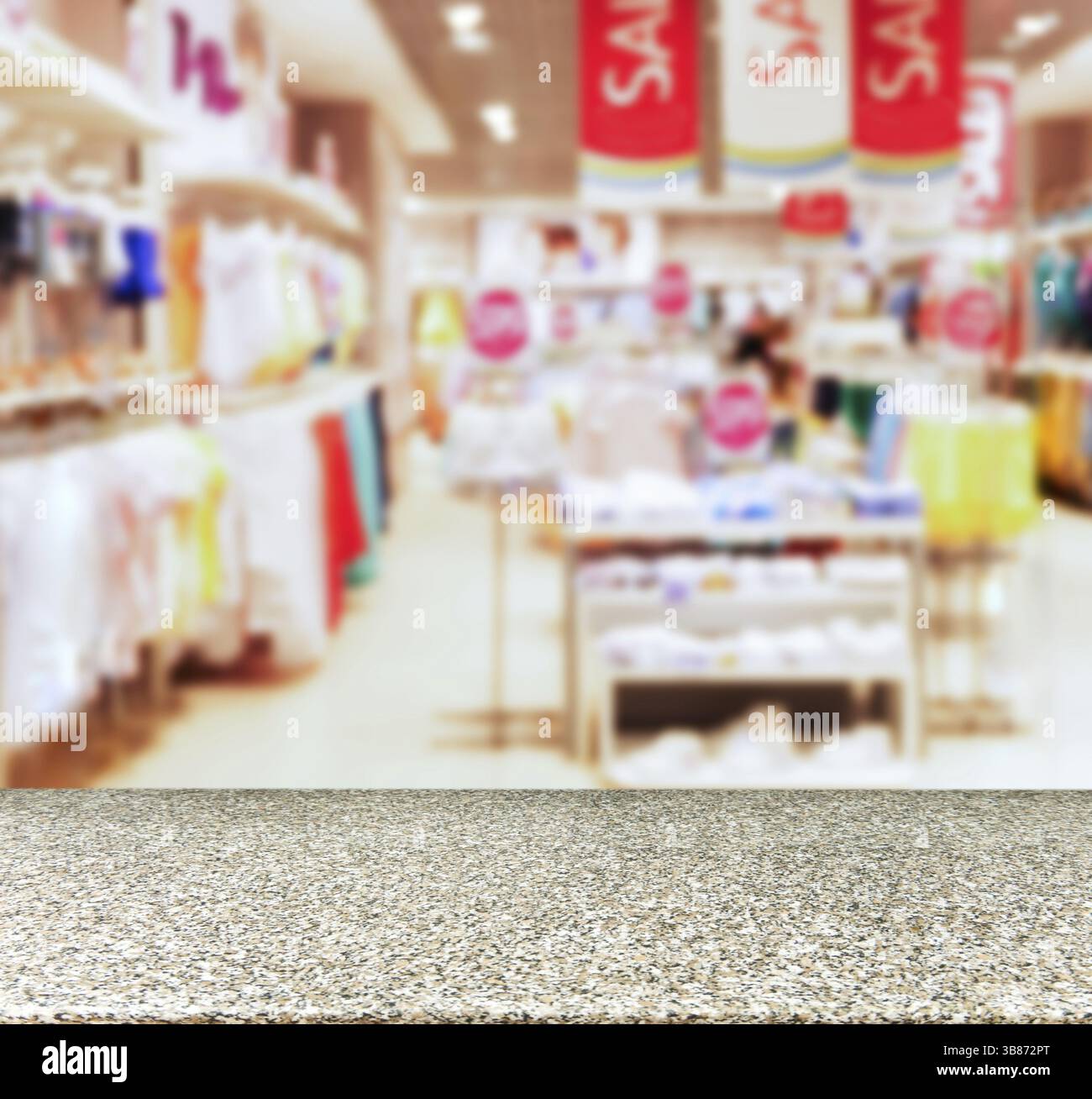 Marmorbrett leerer Tisch vor verschwommenem Hintergrund. Perspektivischer Marmortisch über Unschärfe in Kinderkleidung des departament Store. Modell für Anzeige oder Stockfoto