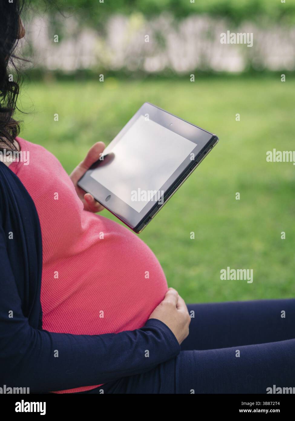Schwangere Frau mit Tablet-E-Reader Stockfoto